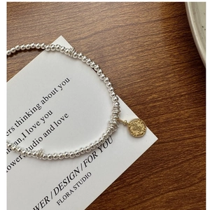 Detailed close-up of a vintage S925 silver beaded necklace with a golden coin pendant charm