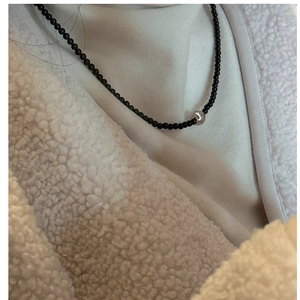 Close-up of S925 sterling silver beaded necklace with black stones on model's neck