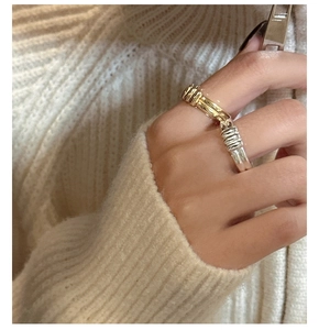 Close-up of stacked gold and silver textured rings with minimalist striped pattern