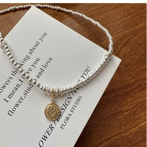 Macro detail of S925 silver beaded necklace with vintage gold coin pendant and zircon