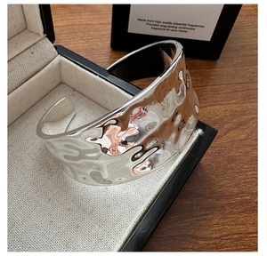 Detailed close-up of wide S925 sterling silver bangle with irregular hammered texture