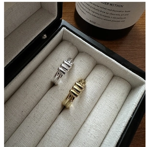 Detailed view of silver and gold textured rings in a jewelry box on a wooden desk