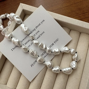 Baroque irregular pearl necklace with metallic luster on beige velvet jewelry tray