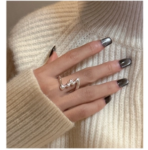 Close-up of wavy liquid silver style S925 sterling silver ring on hand with black nails