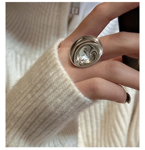Close-up of a wide polished S925 silver ring with a fluid ripple design on a hand