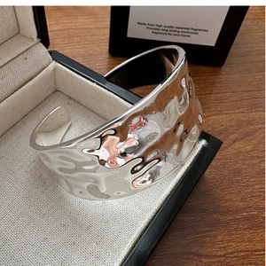 Detailed view of wide C-shape silver bangle featuring hammered texture in a gift box