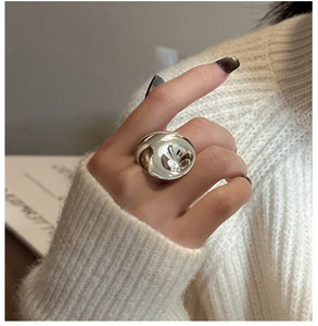 Close-up of irregular liquid metal silver ring on finger with soft knit background