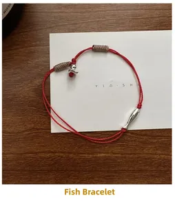Détail d'un bracelet tressé rouge avec breloque poisson en argent et cordon réglable