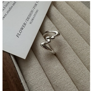 Macro shot of silver S925 ring with irregular wave texture on beige velvet tray