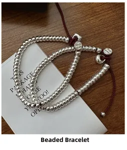 Détail d'un bracelet en argent S925 avec cordon rouge sur fond de bois texturé