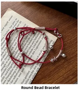Dettaglio di bracciali in corda intrecciata rossa con perle d'argento e campanelli