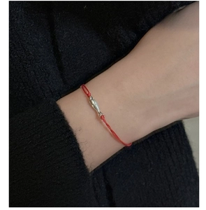 Détail d'un bracelet minimaliste en cordon rouge avec un petit pendentif poisson en argent