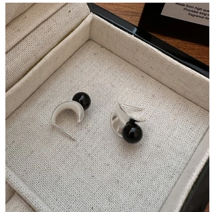 Macro detail of S925 silver C-shaped earrings with polished black onyx bead inlay