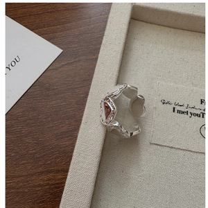 Detail of silver heart-shaped ring featuring dark red gemstone inlay and vintage texture