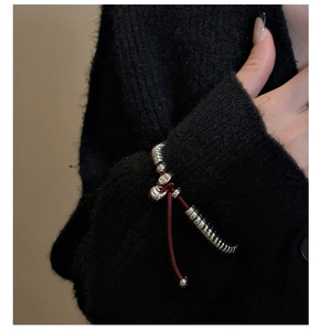 Détail du bracelet perlé en argent S925 avec pendentif cœur et cordon rouge ajustable