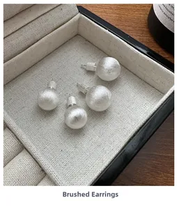 Close-up of S925 sterling silver stud earrings with brushed texture in a jewelry box