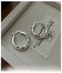 Close-up of S925 sterling silver stamp on textured hoop earrings with a metallic finish