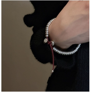 Détail du bracelet en perles d'argent S925 avec cordon rouge sur le poignet d'un mannequin