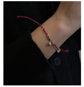 Dettaglio macro del bracciale con filo rosso in argento S925 e ciondolo a campanella