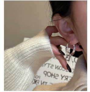 Close-up of polished S925 sterling silver hoop earrings worn with casual white knitwear
