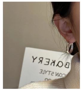 Detail of silver hoop earrings with hammered texture worn on ear for minimalist style