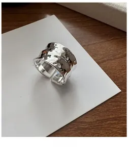 Detailed view of S925 sterling silver wide ring with irregular hammered texture on paper