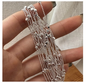 Macro detail of S925 sterling silver beaded chain with cubic charms on hand