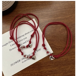 Detail of red braided cord bracelets featuring silver heart pendants on a poem card