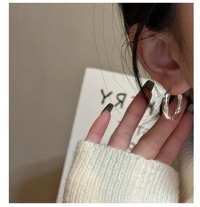 Close-up of minimalist chunky silver hoops worn by model with textured metal finish