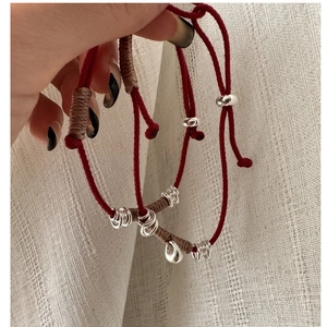 Detail of red braided lucky charm bracelets with silver beads and droplets charms