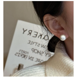 Macro detail of silver round ball stud earring with brushed matte finish on model