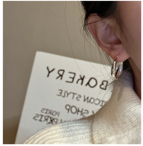 Close-up of silver textured hoop earring on model showing vintage hammer pattern