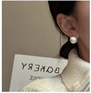 Macro shot of silver spherical stud earring with matte brushed texture for women