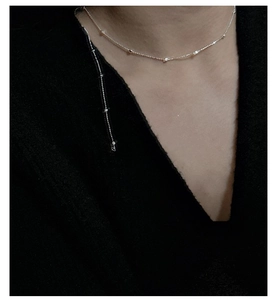 Detail of delicate S925 sterling silver chain with small beads on female neck