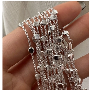 Detail of silver S925 multilayer beaded chain necklace with polished metal texture