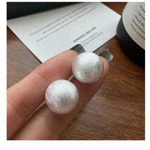 Close-up of S925 sterling silver earrings with brushed texture held by hand