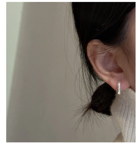 Detail of S925 sterling silver hoop earrings with irregular hammered texture on model