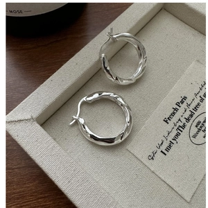 Macro shot of S925 sterling silver hoop earrings with twisted texture on jewelry tray