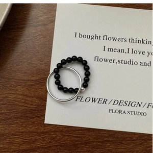 Detailed close-up of a dual-layer silver ring set with polished black beads on card