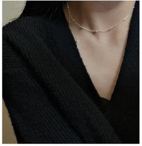 Close-up of minimalist S925 sterling silver beaded chain necklace on a model