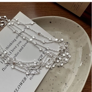 Detail of S925 sterling silver beaded chain layered over aesthetic stationery and ceramics