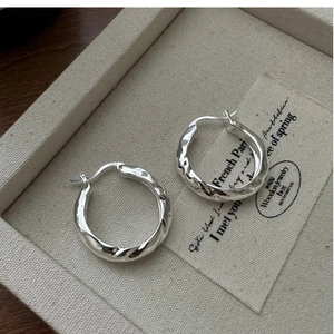 Detail of S925 sterling silver hoop earrings with irregular hammered texture and polish