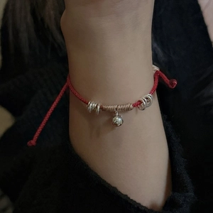Bracciale artigianale in corda rossa con perline d'argento e piccolo ciondolo a campanella
