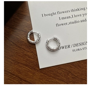 Close-up of S925 sterling silver hoop earrings with irregular molten texture on wood