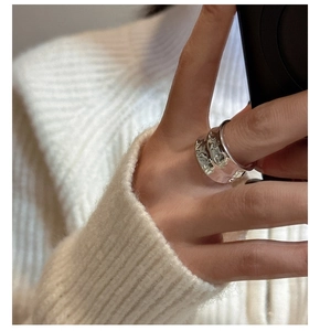 Detail of silver S925 wide band ring with irregular lava texture worn on hand