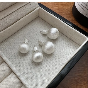 Detailed view of S925 sterling silver ball earrings with brushed matte finish in jewelry box