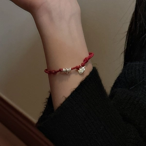 Minimalist red cord bracelet with heart charm and silver bead on a female wrist