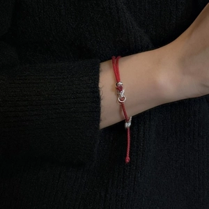 S925 sterling silver red braided rope bracelet with metallic charms on a model wrist
