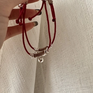 Bracciale a cordoncino rosso intrecciato con perle in argento S925 e ciondolo a campanello