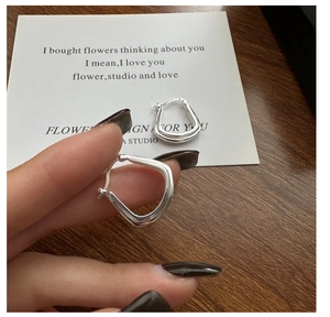Gros plan de boucles d'oreilles carrées géométriques en argent tenues à la main
